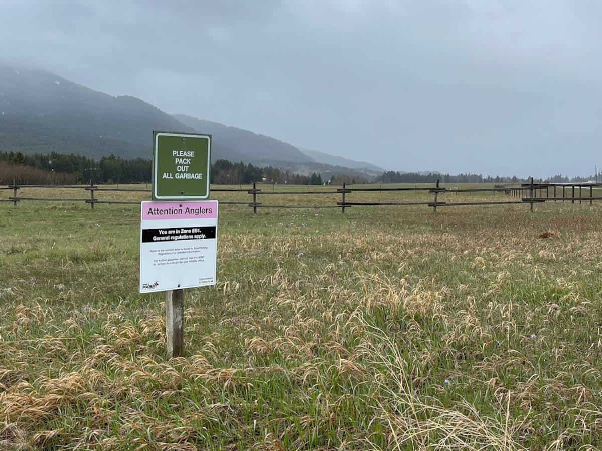 A foggy field with a big sign that says "Attention Anglers". The sign has information below that is too small to read from the picture.