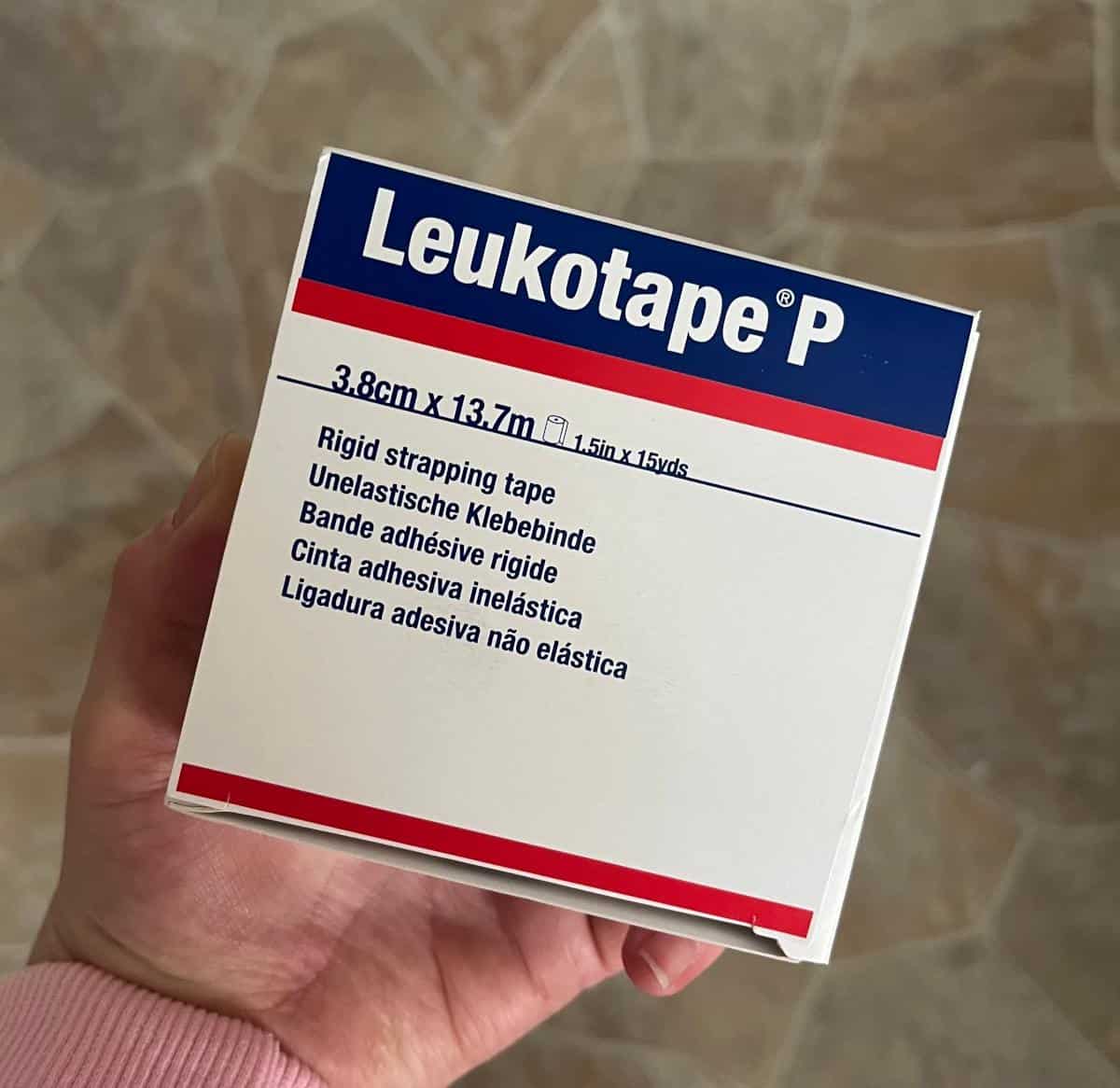 A woman's hand holding a package of Leukotape.