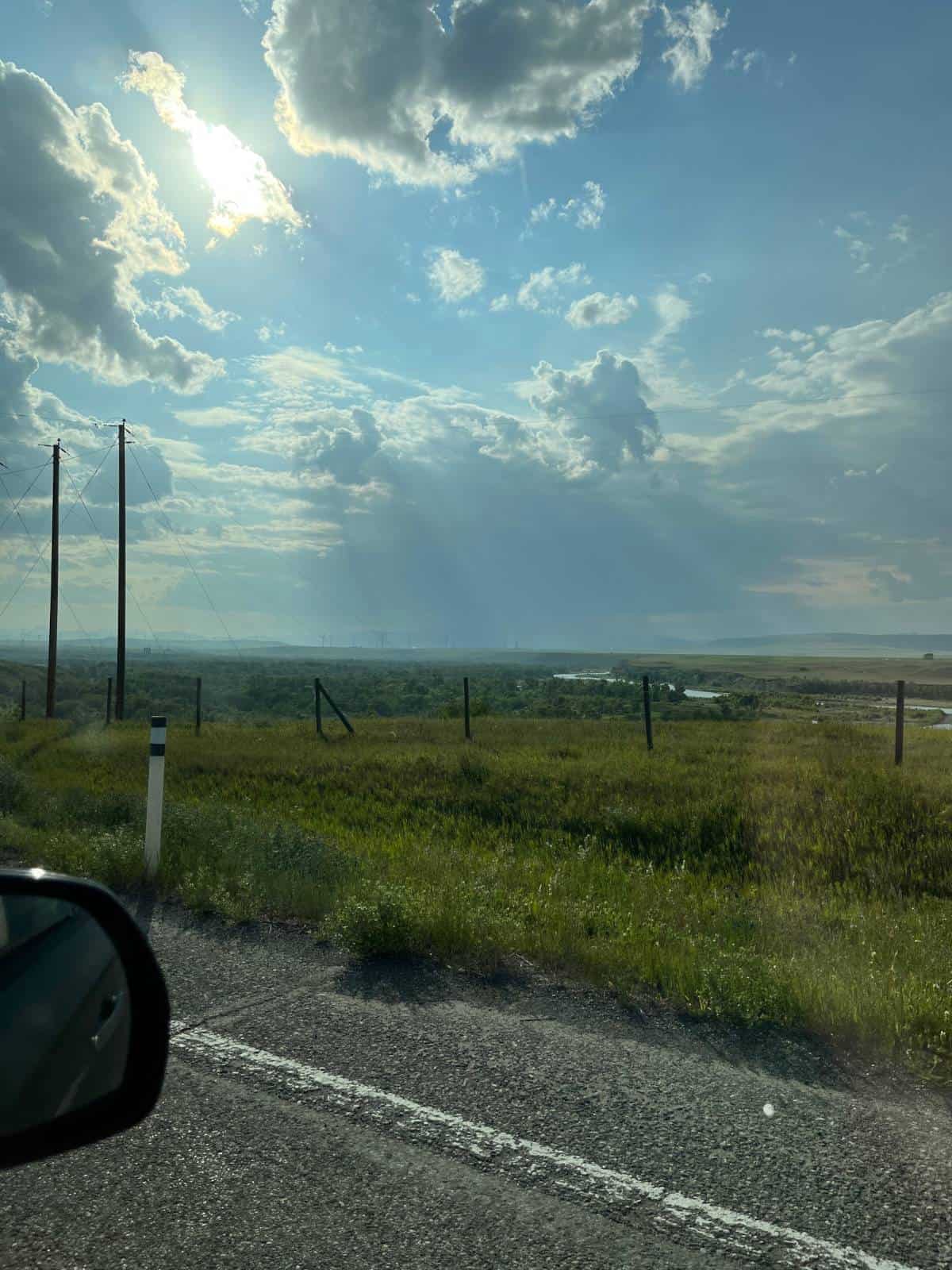 The view out of the passenger window, looking out on to a vast prairie with a river and windmills in the distance.