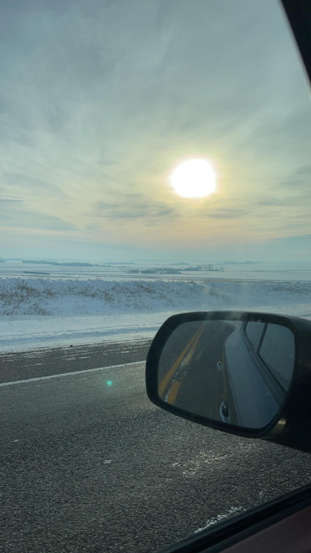 A snowy prairie, as viewed from the driver's seat.