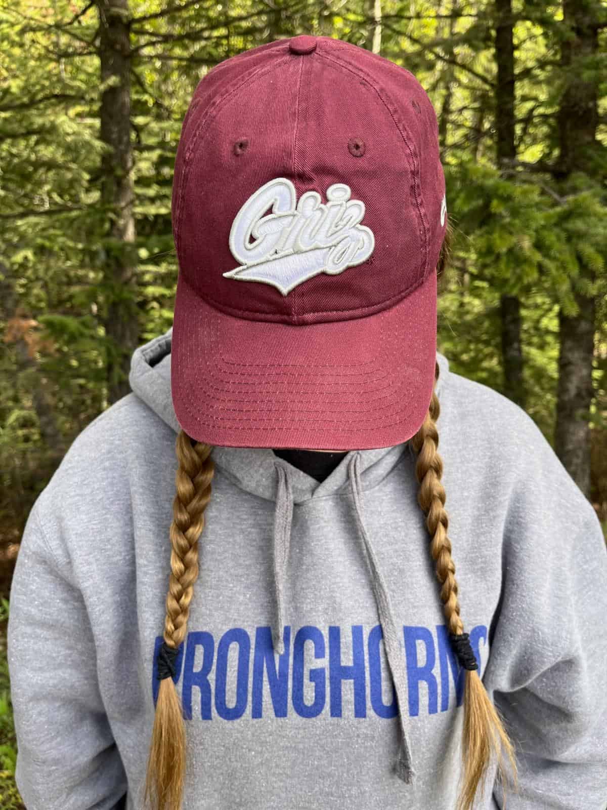 A girl with braids and a Montana Griz baseball cap.