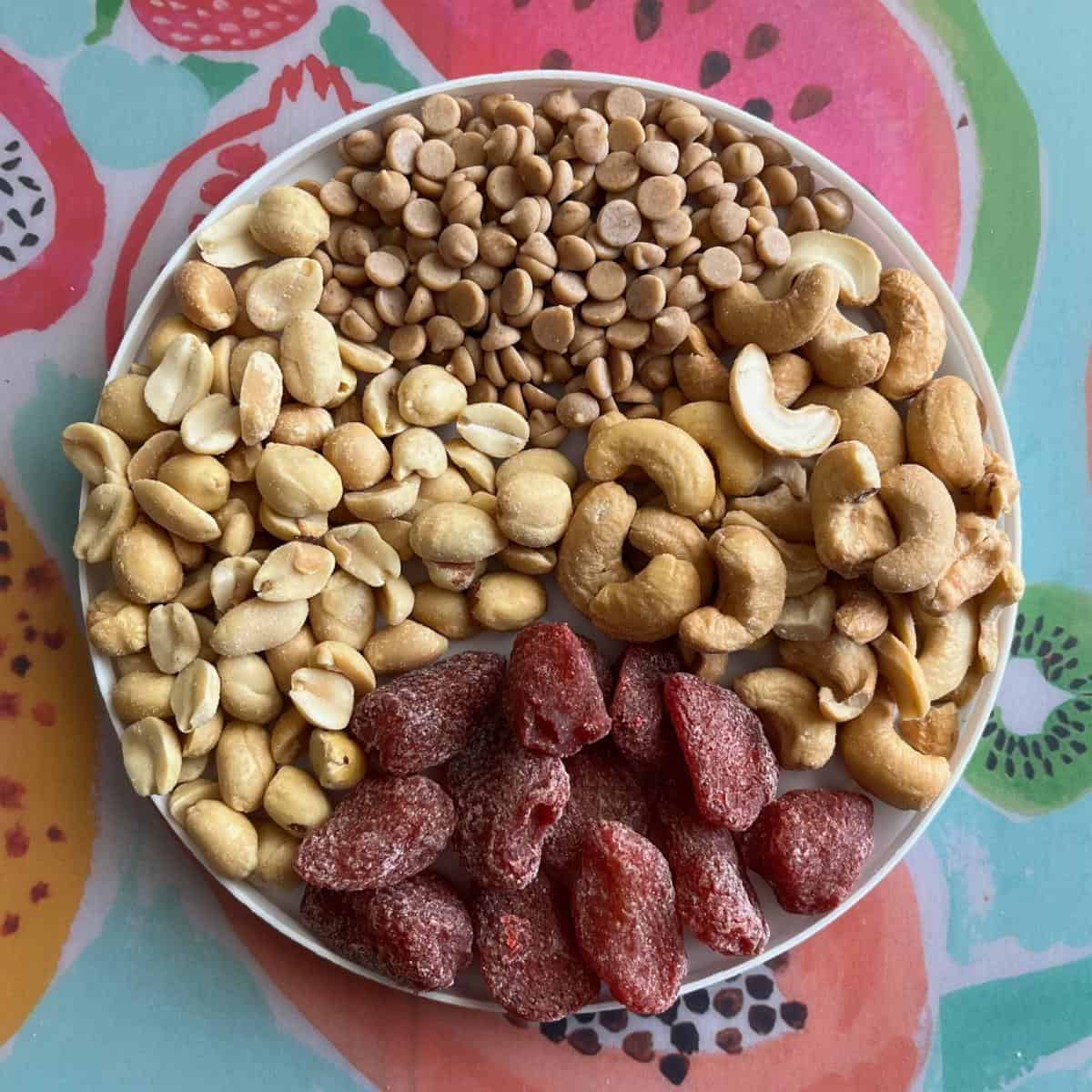 A plate with peanuts, dried strawberries, cashews, and peanut butter chips.