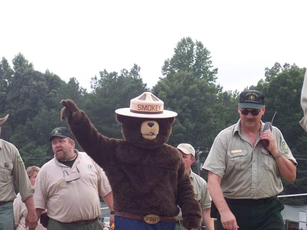 Smokey Bear waves while surrounded by US Forest Service workers.